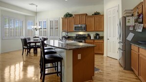 A spacious kitchen with wooden cabinets, a central island, and a dining area with bar stools. - 2400 sq. ft., 4 bedroom, 2 bath, sleeps 8, hot tub (Goodyear)