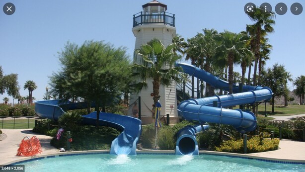 A water park with a lighthouse in the background, a pool, and multiple slides. - 2400 sq. ft., 4 bedroom, 2 bath, sleeps 8, hot tub (Goodyear)