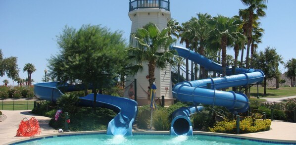 A water park with a lighthouse in the background, a pool, and multiple slides.