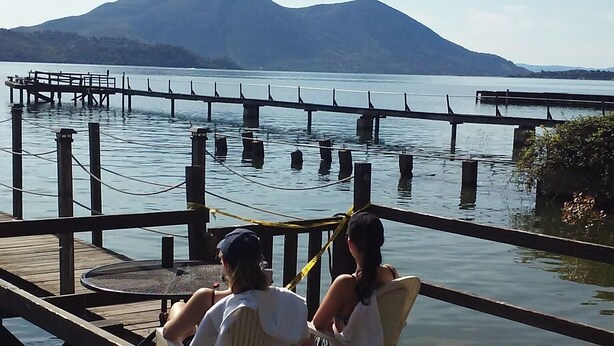 Une jetée en bois s’étendant au-dessus d’une étendue d’eau calme, avec des montagnes en arrière-plan.