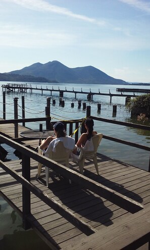 A wooden pier extending over calm water with mountains in the background. - Lake front unit #6 right by the water (Clearlake)