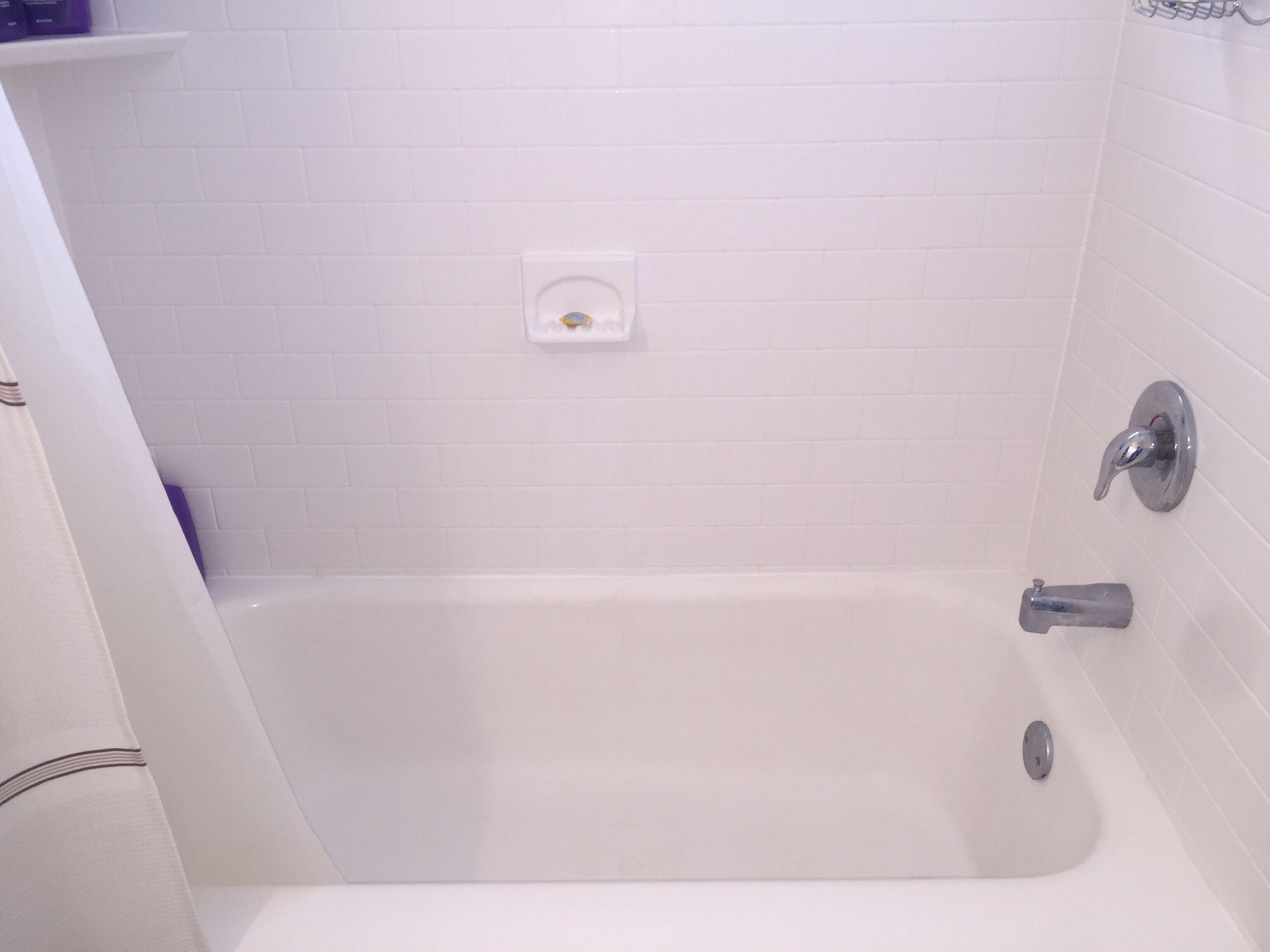 A white bathtub with a chrome faucet and a small control panel on the wall.