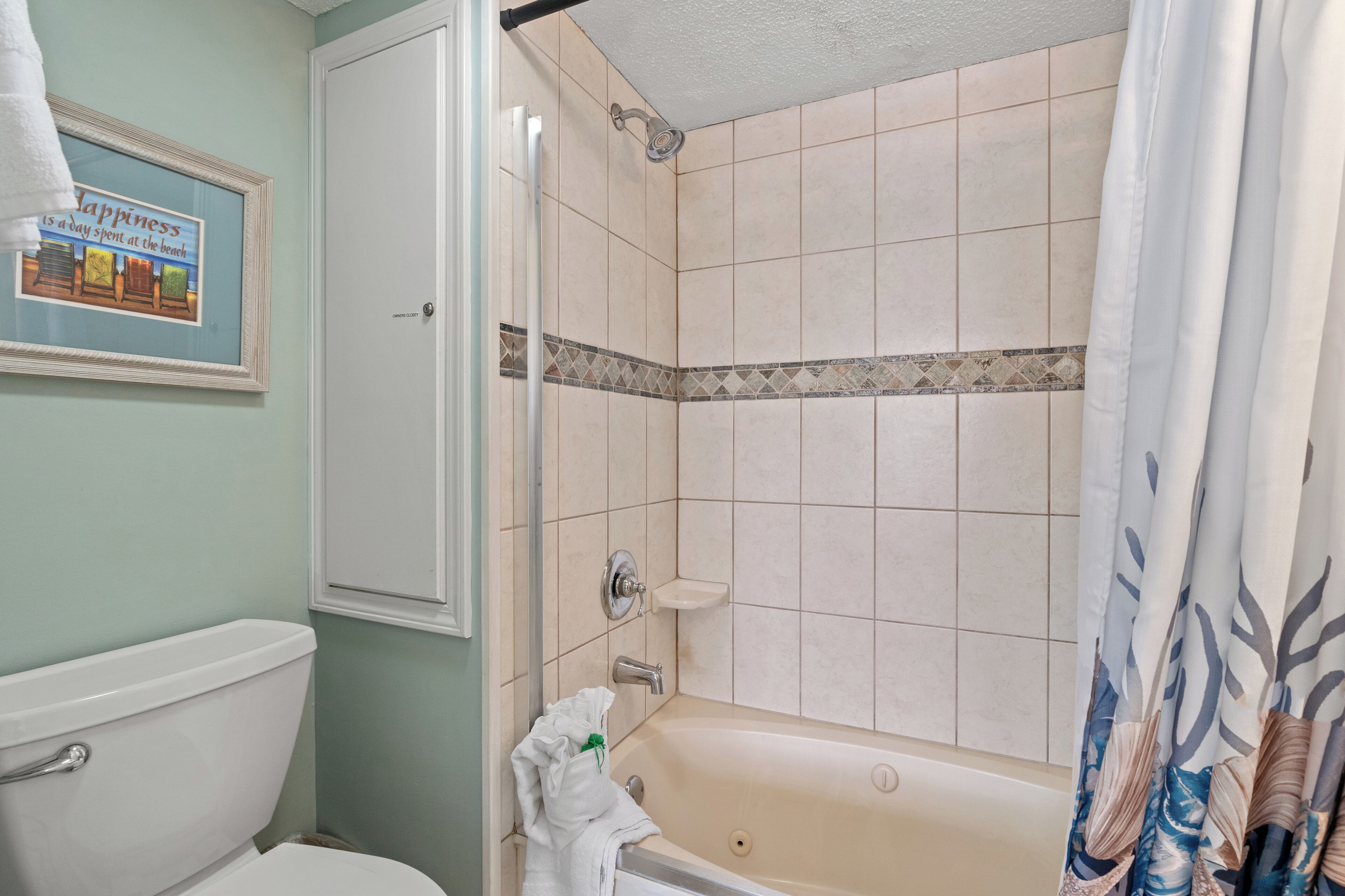 Une salle de bain avec des toilettes, une douche avec un mur carrelé et un tableau encadré accroché au mur.