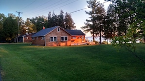 Een houten huis met twee verdiepingen, een overdekte veranda en uitzicht op het water.