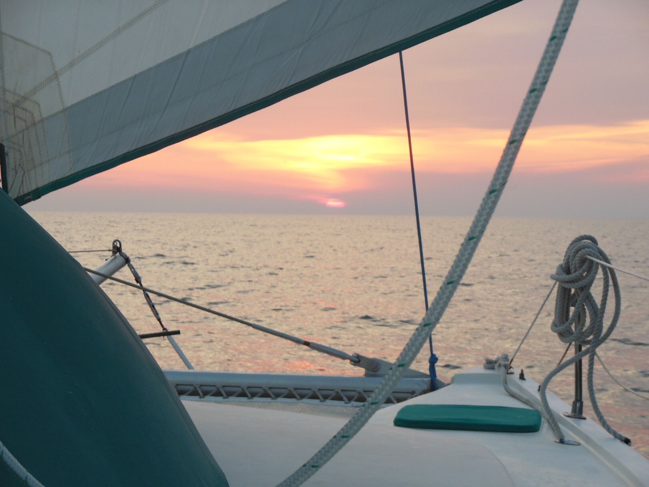 Ein Segelboot mit Blick auf den Sonnenuntergang über dem Meer.