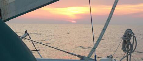 Ein Segelboot mit Blick auf den Sonnenuntergang über dem Meer.