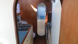 A narrow, wooden-lined kitchen with a sink, a stove, and a refrigerator. - Sailing catamaran vacation rentals in Pensacola Beach (Pensacola Beach)