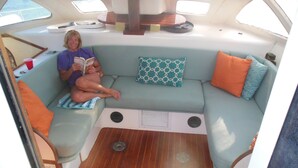 A cozy interior with a sofa, pillows, and a small table. - Sailing catamaran vacation rentals in Pensacola Beach (Pensacola Beach)