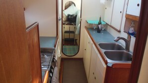 A compact kitchen with a sink, a small countertop, and a stove. - Sailing catamaran vacation rentals in Pensacola Beach (Pensacola Beach)
