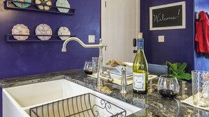 Une cuisine avec un évier, une bouteille de vin et des verres à vin.