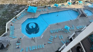Luchtbeeld van een zwembadgedeelte met meerdere zwembaden, ligbedden en parasols.