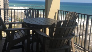 Een balkon met tafel en stoelen met uitzicht op het strand.
