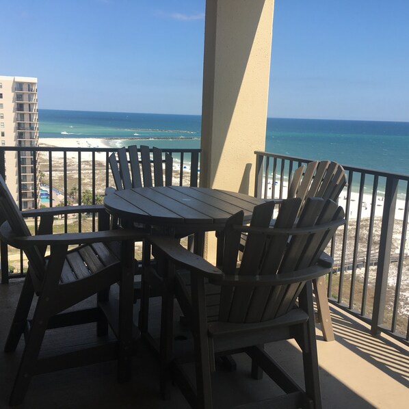 Un balcon avec une table et des chaises donnant sur une plage.