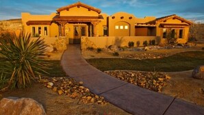 A two-story house with a stone facade, a covered patio, and a landscaped yard with rocks and a pathway. - Spectacular Home Near Zion with Pool and Hot Tub (Virgin)