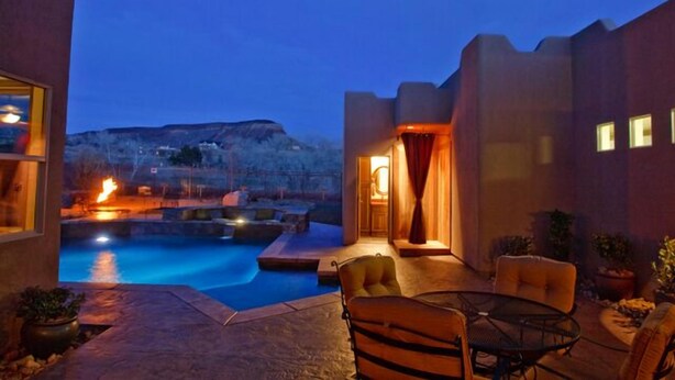 A modern outdoor pool area with a stone patio, lounge chairs, and a view of a mountain. - Spectacular Home Near Zion with Pool and Hot Tub (Virgin)
