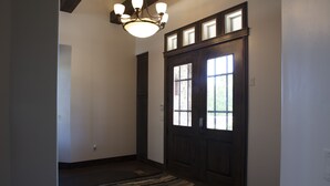 A hallway with a dark wooden door, a light fixture, and a striped rug. - Spectacular Home Near Zion with Pool and Hot Tub (Virgin)
