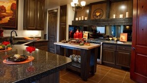 A kitchen with dark wood cabinets, a granite countertop, a chandelier, and a clock on the wall. - Spectacular Home Near Zion with Pool and Hot Tub (Virgin)