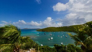 Vista costera con barcos, agua cristalina y palmeras.
