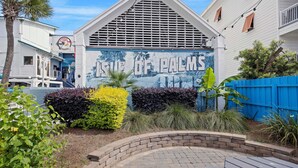 Een gebouw met een muurschildering getiteld 'SIEGE OF PALMS' en een blauwe omheining.