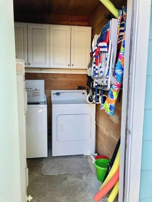 A compact laundry room with a washing machine, dryer, and cabinets. - Pass-a-Grille Gulf Front Cottage, Ocean View (St Pete Beach)
