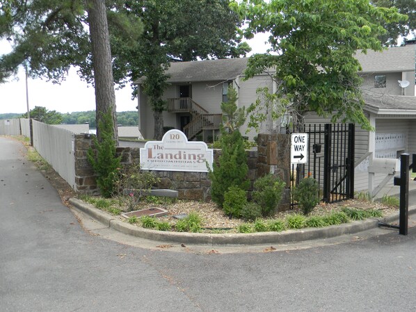 A gated property entrance with a sign indicating 'The Landing Condominiums' and a 'One Way' sign.
