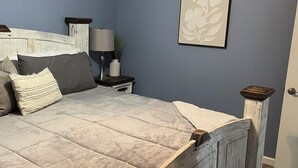 A bedroom with a bed, a nightstand, a lamp, a framed floral artwork, and a ceiling fan. - Off Season Rates!  Ideal location on Lake Hamilton! (Lake Hamilton)