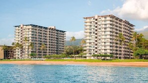 A beachfront hotel with multiple floors, balconies, and a pool.