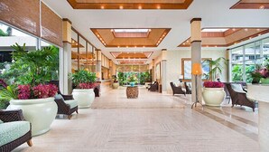 A spacious lobby with a high ceiling, large windows, and a variety of seating arrangements.