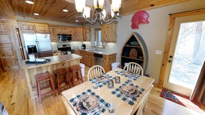 A wooden interior with a kitchen, dining area, and a large window.