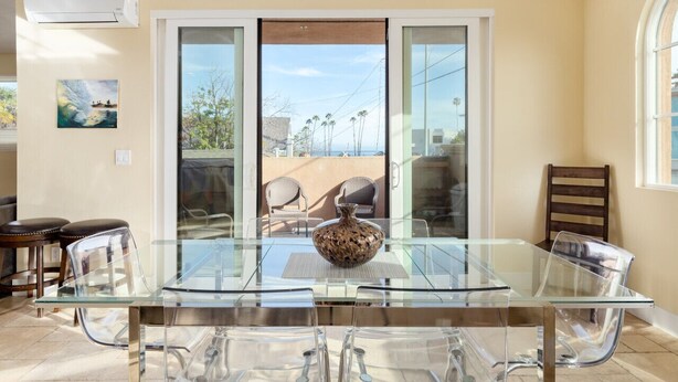 A glass-top dining table with clear chairs, a vase, and a view of the outdoors through a sliding glass door. - Luxurious Ocean 4bd/3ba Oceanview Villa (Santa Cruz)
