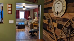 Ein Wohnzimmer mit einer Holz-Wanduhren, einem Sofa, einem Couchtisch und einer Bank.