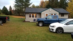 Ein Haus mit Garage, ein blauer Lkw und ein weißes Auto vor der Tür.