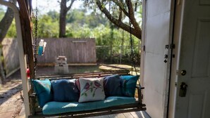 A wooden deck with a swing chair and a white door. - Turtle Time - 4 Bd House Near Holden Beach - escape the crowds! (Supply)
