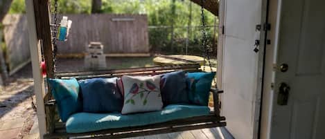 A wooden deck with a swing chair and a white door.