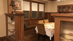 Un comedor con muebles de madera, una mesa con mantel floral y una estantería con libros y adornos.