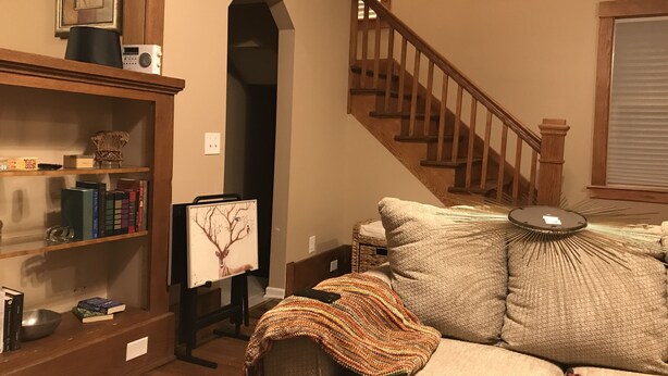 Una sala de estar acogedora con una escalera de madera, una estantería y un sofá cómodo.