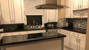 Una cocina moderna con armarios blancos, encimera negra y una isla de cristal.