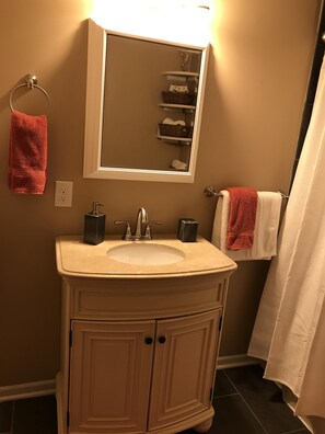 Un baño con lavamanos, espejo, toallero y cortina de ducha.