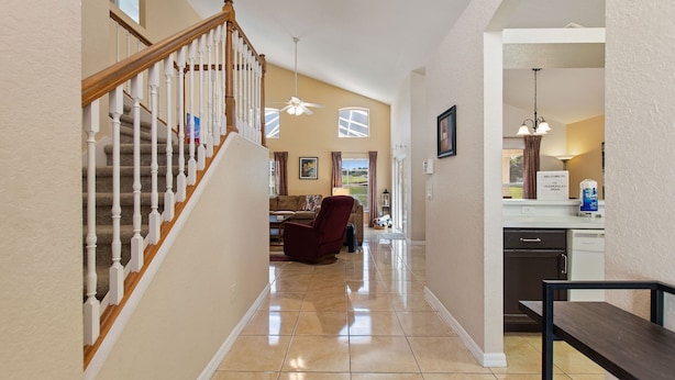 A spacious hallway with a wooden staircase, a dining area, and a kitchen. - Golf Course View Villa! Just 25 mins to Disney Magic (Davenport)