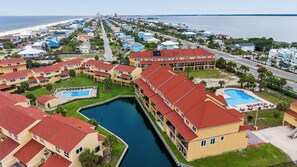 A coastal hotel with multiple buildings, a marina, and a beach in the background.
