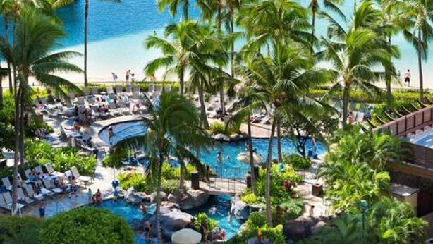 Een resort met een strand, palmbomen en een zwembad.