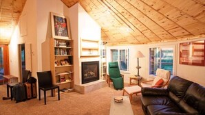 A cozy living room with a fireplace, a bookshelf, a green armchair, and a leather sofa. - Visit award winning wineries in our valley in tricked out Yurt on the NF River. (Hotchkiss)