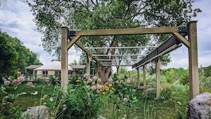 A wooden pergola structure in a garden with various plants and flowers. - Visit award winning wineries in our valley in tricked out Yurt on the NF River. (Hotchkiss)