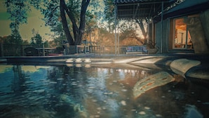 A serene outdoor pool area with a stone bench, a wooden pergola, and a view of a building with a glass door. - Visit award winning wineries in our valley in tricked out Yurt on the NF River. (Hotchkiss)