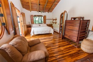 A bedroom with a wooden floor, a bed, a dresser, and a chair.