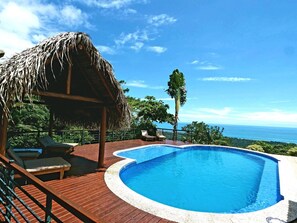 Una piscina con muelle de madera y una estructura de techo de paja.