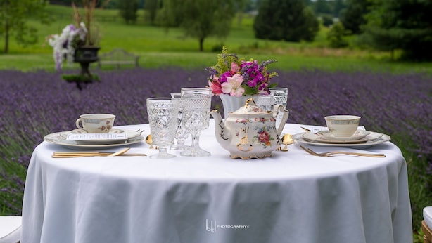 Mesa redonda preparada para tomar té, con adornos florales y vistas a un campo de lavanda.