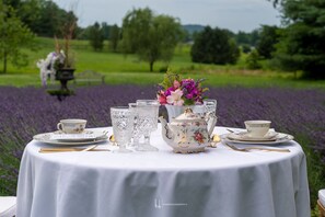 A round table set for tea with floral decorations and a view of a lavender field.