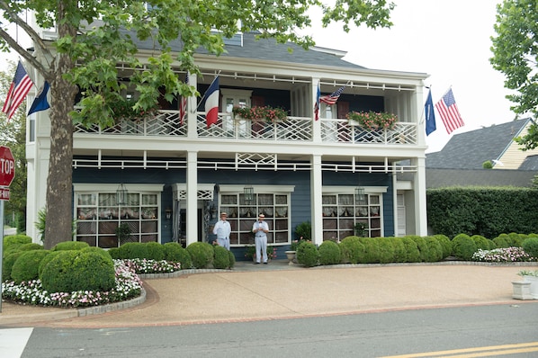 A two-story building with a balcony, flags, and a stop sign.