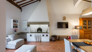 A cozy kitchen with a stone oven, a dining table with a fruit basket, and a TV mounted on the wall. - Welcome to G-HOUSE in FLORENCE  (Firenze)